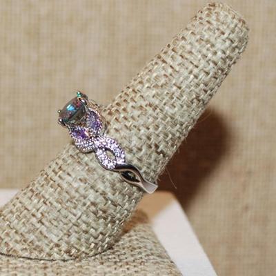 Size 7 ½ Iridescent Round Main 4 Prong Stone Ring with 4 "Leaves" of Light Purple Accent Stones on a Silver Tone Band (2.9g)