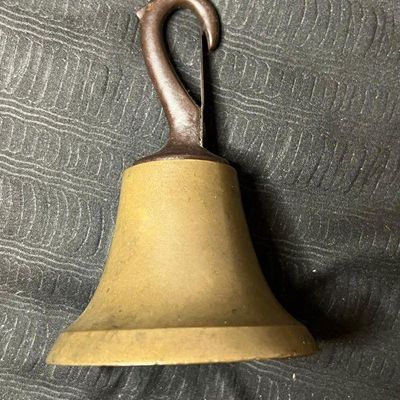 Vintage brass hand bell featuring a dark metal hook handle, showing a natural aged patina.