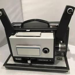 Vintage Kodak Chevron 8 movie projector, featuring a black and silver casing with dual reel arms and a carrying handle.