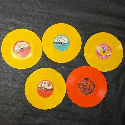 Collection of vintage children's 78 RPM records, including four yellow Golden Records and one orange record, showing some wear from...