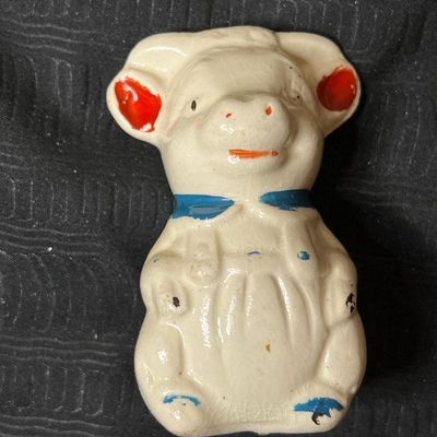 Vintage ceramic pig figurine featuring hand-painted red ears and a blue collar, showing some crazing and paint wear consistent with age.