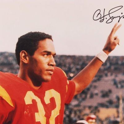 Autographed color photograph of O.J. Simpson in his USC Trojans football uniform, featuring a signature in the upper right corner.