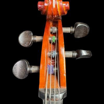Sale Photo Thumbnail #4: This piece is a high quality student cello. There are areas of scuffs, missing veneer, and minimal wood loss ath the base and around the edges. There is Sharpie writing on the reverse. Measurement: 38” x 12”. Pre-auction estimate: $750-$1000. [MI]