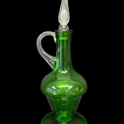 Sale Photo Thumbnail #24: This mid-century hand-blown art glass decanter is believed to be made by the Bischoff Glass Company in the 1950s or 1960s. The color is vibrant emerald green. There is a rough pontil mark on the base, a clear applied handle, and a clear flame-shaped stopp