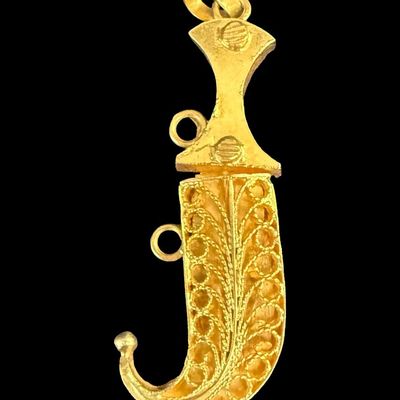 Sale Photo Thumbnail #59: This two-piece pendant is crafted from 18K yellow gold. The scabbard features intricate filigree. The clasp needs to be adjusted, and the safety chain is missing. The overall length is 1 3/8” long, and the weight is 2.79 grams. The gold content was conf