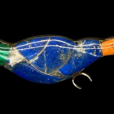Sale Photo Thumbnail #62: This unsigned brooch is believed to be Zuni, and features tessellated lapis, jasper, carnelian, and malachite, set in .950 silver. It measures 2 5/8” long, and weighs 10.16 grams. Silver content was confirmed with testing. Pre-auction estimate: $50-$100