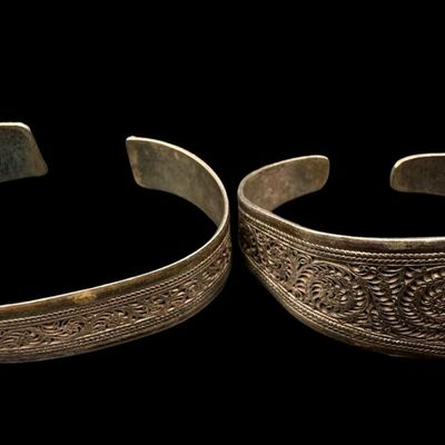 Sale Photo Thumbnail #64: These bracelets have applied filigree, with intricate scrolling. Both pieces are marked “925.” The largest cuff measures 3” wide by 1.25” high. Both cuffs are bent somewhat. The total weight is 76.15 grams. [AG]