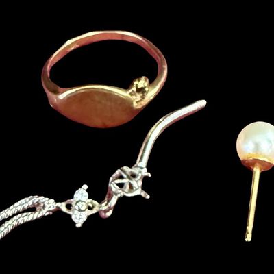 Sale Photo Thumbnail #70: This 10K gold assortment includes a vintage signet ring that is missing a stone and appears to have a worn down monogram; a single pearl stud earring; and a belly button ring that is missing the top ball. The ring size is 4.25. The total weight is 2.32 gr