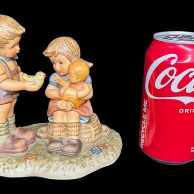 Sale Photo Thumbnail #135: This 1999 piece is numbered BH 80, and was created in Thailand. It depicts a young boy standing and showing a small yellow songbird to a sitting girl who is cradling a doll or baby. Includes the original box. Measurement of figurine: 5.5” x 6”. [AG]