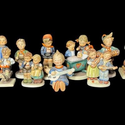 Sale Photo Thumbnail #340: Includes a total of 15 Hummel figurines. All were made by Goebel of Germany. There may or may not be flea bites on some pieces. Some pieces have been repaired. Measurement of tallest: 6”H. [AG]