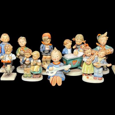 Sale Photo Thumbnail #337: Includes a total of 15 Hummel figurines. All were made by Goebel of Germany. There may or may not be flea bites on some pieces. Some pieces have been repaired. Measurement of tallest: 6”H. [AG]