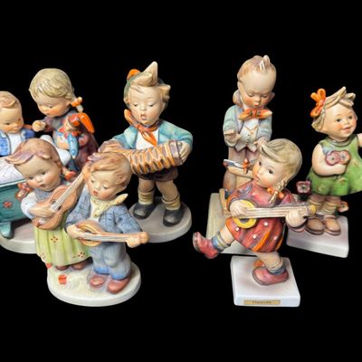 Sale Photo Thumbnail #338: Includes a total of 15 Hummel figurines. All were made by Goebel of Germany. There may or may not be flea bites on some pieces. Some pieces have been repaired. Measurement of tallest: 6”H. [AG]