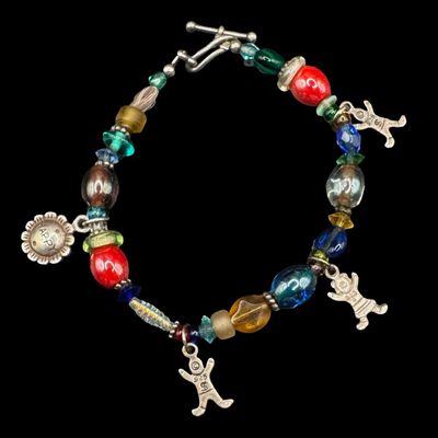 Sale Photo Thumbnail #354: This bracelet features multi-colored beads, sterling silver charms, and sterling silver accents and clasp. Some components are marked “925.” The silver content of other components was confirmed with testing. The clasp needs repair. The overall weight 