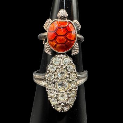 Sale Photo Thumbnail #356: Includes a vintage Meka of Denmark adjustable enameled turtle ring, and a cluster ring with clear stones (size 8.75). Both rings are marked “Sterling.” The total weight is 7.67 grams. [PM]