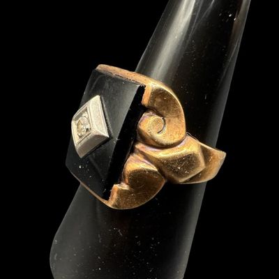 Sale Photo Thumbnail #369: This ring features a rectangular piece of black onyx set in a yellow gold frame. A round diamond is set in a white gold frame in the center of the black onyx. The ring size is 9. The ring is somewhat out of round. The weight is 6.51 grams. [PM]