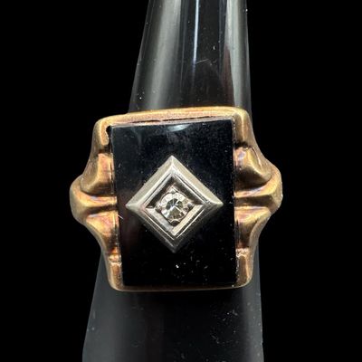 Sale Photo Thumbnail #367: This ring features a rectangular piece of black onyx set in a yellow gold frame. A round diamond is set in a white gold frame in the center of the black onyx. The ring size is 9. The ring is somewhat out of round. The weight is 6.51 grams. [PM]