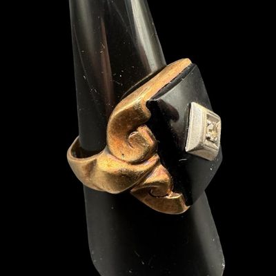 Sale Photo Thumbnail #368: This ring features a rectangular piece of black onyx set in a yellow gold frame. A round diamond is set in a white gold frame in the center of the black onyx. The ring size is 9. The ring is somewhat out of round. The weight is 6.51 grams. [PM]