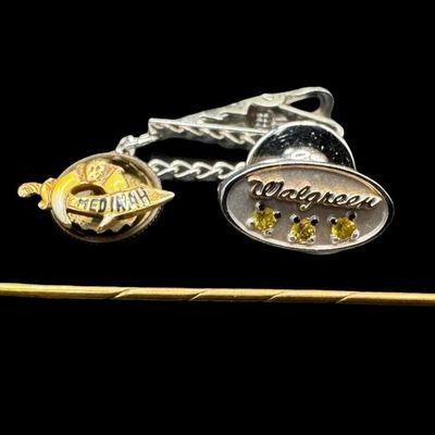Sale Photo Thumbnail #431: Includes a 14K yellow gold stick pin with a garnet, a 10K yellow gold Shriners pin, and a 10K white gold “Walgreen” pin with three citrine stones. Weight of 14K: 1.33 grams. Weight of 10K: 2.07 grams. The pin backs were removed before weighing. The go