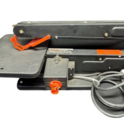 Sale Photo Thumbnail #435: The C-frame arm provides a wide throat capacity for maneuvering materials. The work table tilts to accommodate angled cuts. The saw is working at the time of catalog. Measurement: 23”L x 9.75”W x 9.75”H. [RS]
