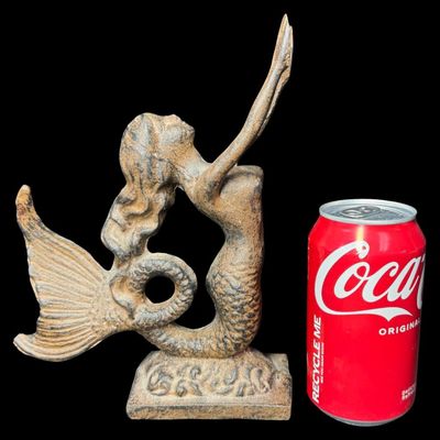Sale Photo Thumbnail #572: This piece features a cast mermaid with outstretched arms on a heavy base. There is minimal surface rust. Measurement: 9” x 6.5”. [AG]