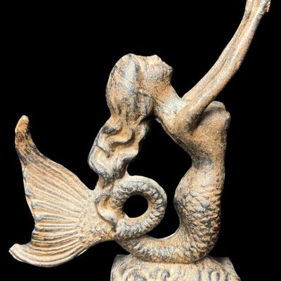 Sale Photo Thumbnail #570: This piece features a cast mermaid with outstretched arms on a heavy base. There is minimal surface rust. Measurement: 9” x 6.5”. [AG]