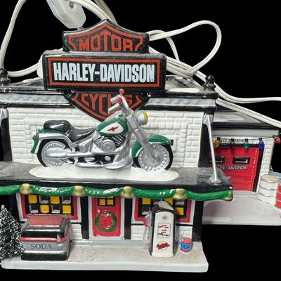 Sale Photo Thumbnail #638: From the original Snow Village Series. This retired set features a hand painted ceramic building along with detailed accessory pieces. Total of four pieces. This may or may not be complete. The separate HD sign with motorcycle on top has been repainted (p