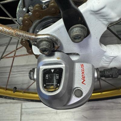 Sale Photo Thumbnail #650: This is constructed of a lightweight aluminum step-through frame, with distinct gold script accents. It features front and rear hand-operated side pull caliper brakes. It is gently used, though there may be stains or pitting in places. [AG]