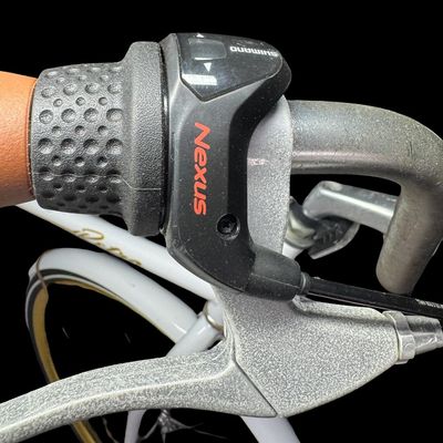 Sale Photo Thumbnail #651: This is constructed of a lightweight aluminum step-through frame, with distinct gold script accents. It features front and rear hand-operated side pull caliper brakes. It is gently used, though there may be stains or pitting in places. [AG]