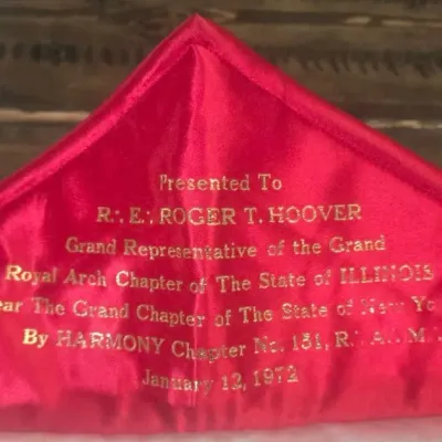 Sale Photo Thumbnail #238: A striking Masonic Royal Arch Past High Priest apron, rich in symbolism and finely detailed with gold bullion embroidery on satin.

Royal Arch Symbolism: The apron includes the characteristic red border and the emblem of the Royal Arch
Embroidered Detail: