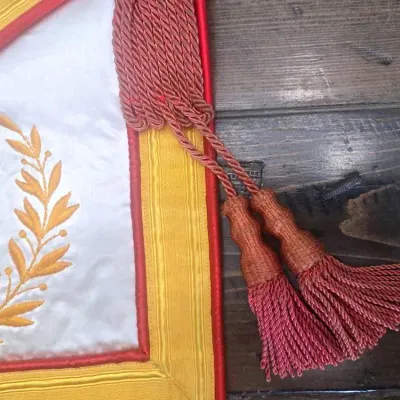 Sale Photo Thumbnail #237: A striking Masonic Royal Arch Past High Priest apron, rich in symbolism and finely detailed with gold bullion embroidery on satin.

Royal Arch Symbolism: The apron includes the characteristic red border and the emblem of the Royal Arch
Embroidered Detail: