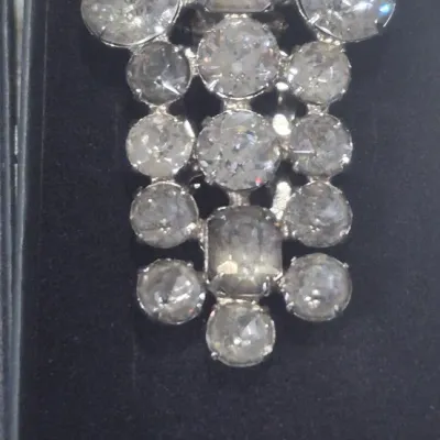 Sale Photo Thumbnail #203: A beautiful vintage rhinestone fur clip in the unmistakable Eisenberg style, featuring a bold, dimensional arrangement of faceted clear stones in a classic silver-tone setting. The design showcases a mix of round and rectangular cuts, creating depth, bril