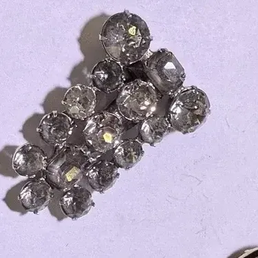 Sale Photo Thumbnail #202: A beautiful vintage rhinestone fur clip in the unmistakable Eisenberg style, featuring a bold, dimensional arrangement of faceted clear stones in a classic silver-tone setting. The design showcases a mix of round and rectangular cuts, creating depth, bril
