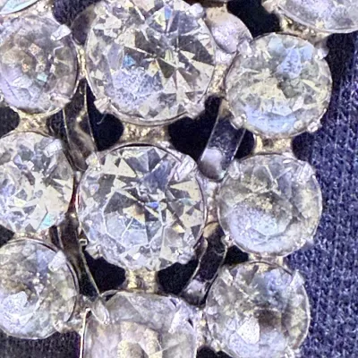 Sale Photo Thumbnail #198: A beautiful vintage rhinestone fur clip in the unmistakable Eisenberg style, featuring a bold, dimensional arrangement of faceted clear stones in a classic silver-tone setting. The design showcases a mix of round and rectangular cuts, creating depth, bril