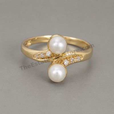 Sale Photo Thumbnail #13: Graceful yellow-gold bypass ring set with two cultured pearl-style cabochons and small round diamond-style accents along the sweeping shoulders. Marked 14K; approximate ring size 7 and estimated gross weight 4.1 grams. Pearls show good luster with minor s