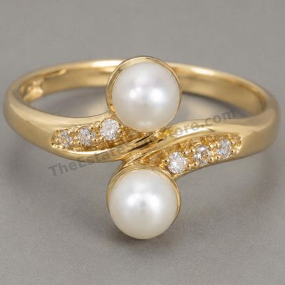Sale Photo Thumbnail #14: Graceful yellow-gold bypass ring set with two cultured pearl-style cabochons and small round diamond-style accents along the sweeping shoulders. Marked 14K; approximate ring size 7 and estimated gross weight 4.1 grams. Pearls show good luster with minor s