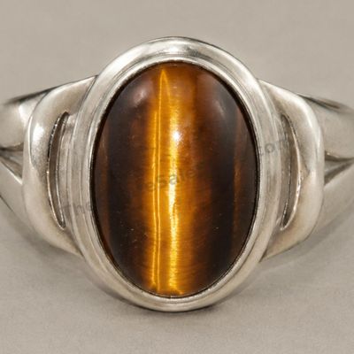 Sale Photo Thumbnail #16: Heavy sterling silver men's ring set with a large oval tiger's-eye-style cabochon displaying a strong golden chatoyant band. Smooth bezel and simple split-shoulder design. Marked 925; approximate ring size 11 and estimated gross weight 14.8 grams. Light s