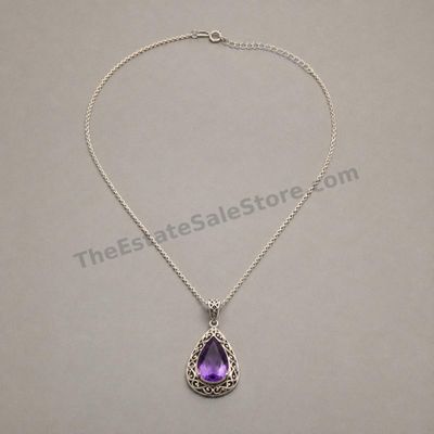 Sale Photo Thumbnail #27: Decorative sterling silver teardrop pendant set with a faceted purple amethyst-style stone in an open scrollwork frame. Suspended from an adjustable 18- to 20-inch cable chain. Marked 925; estimated combined gross weight 9.7 grams. Clean condition with li