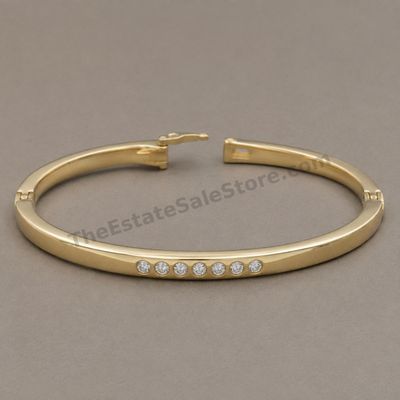 Sale Photo Thumbnail #29: Polished yellow-gold hinged bangle bracelet accented across the front with seven round diamond-style stones in flush settings. Features a box clasp with safety catch. Interior circumference approximately 7 inches; marked 14K; estimated gross weight 11.9 g