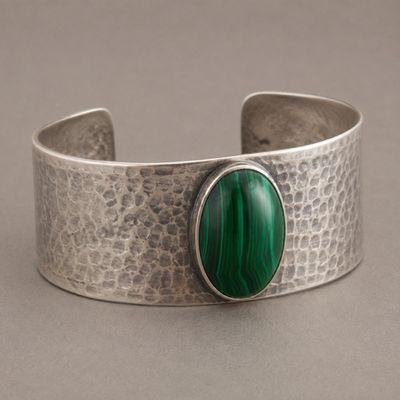 Sale Photo Thumbnail #31: Wide open-back sterling silver cuff with hand-hammered texture and a central oval malachite-style cabochon showing vivid green banding. Approximate interior circumference 6.5 inches with a 1.25-inch opening; estimated gross weight 42.3 grams. Marked 925. 