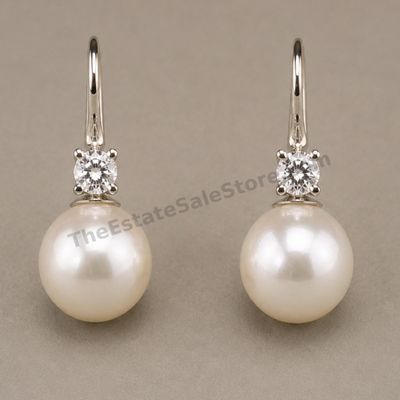 Sale Photo Thumbnail #34: Matched pair of white-gold drop earrings, each featuring a round diamond-style accent above a luminous cultured pearl-style drop. Lever-back ear wires provide secure closure. Marked 14K; approximate drop length 1 inch and estimated combined gross weight 4