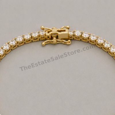 Sale Photo Thumbnail #42: Flexible yellow-gold line bracelet set with approximately forty-two round diamond-style stones in individual four-prong links. Approximate wearable length 7 inches with box clasp and twin safety catches. Marked 14K; estimated gross weight 10.7 grams. Good