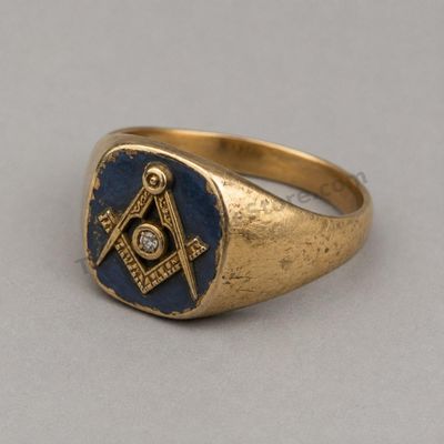Sale Photo Thumbnail #43: Heavy yellow-gold men's ring with a dark blue enamel-style face displaying a raised square-and-compass motif and small diamond-style center accent. Marked 10K; approximate ring size 11.25 and estimated gross weight 9.8 grams. Noticeable scratches, softene