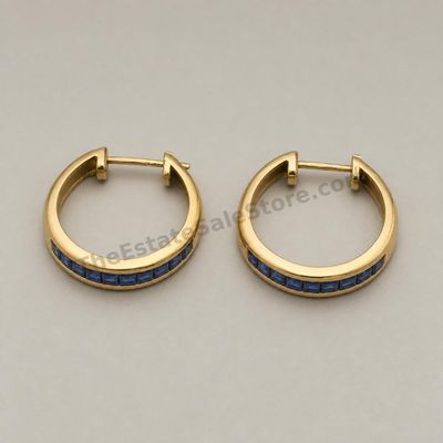 Sale Photo Thumbnail #47: Matched pair of medium-size yellow-gold hoop earrings, each channel-set with a row of square blue sapphire-style stones. Hinged posts close securely. Marked 14K; approximate diameter 22 mm and estimated combined gross weight 5.6 grams. Light wear and mino