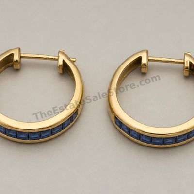 Sale Photo Thumbnail #48: Matched pair of medium-size yellow-gold hoop earrings, each channel-set with a row of square blue sapphire-style stones. Hinged posts close securely. Marked 14K; approximate diameter 22 mm and estimated combined gross weight 5.6 grams. Light wear and mino