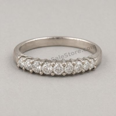 Sale Photo Thumbnail #55: White-gold anniversary band set across the top with seven graduated round diamond-style stones in shared-prong settings. Marked 18K; approximate ring size 6.5 and estimated gross weight 4.3 grams. Fine scratches and slight dulling are visible around the l