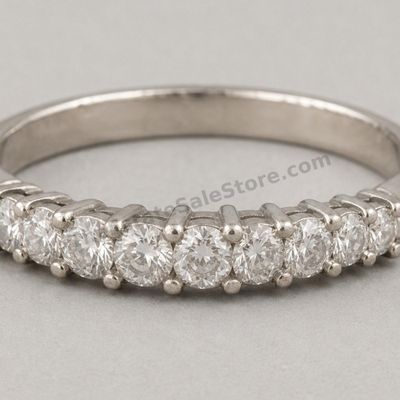 Sale Photo Thumbnail #56: White-gold anniversary band set across the top with seven graduated round diamond-style stones in shared-prong settings. Marked 18K; approximate ring size 6.5 and estimated gross weight 4.3 grams. Fine scratches and slight dulling are visible around the l