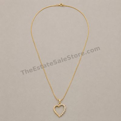 Sale Photo Thumbnail #63: Polished yellow-gold open-heart pendant accented along one side with graduated round diamond-style stones, suspended from an 18-inch box chain. Marked 14K; estimated combined gross weight 5.1 grams. The pendant reverse shows fine scratches from contact wi