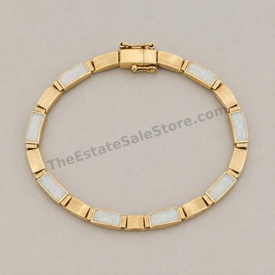 Sale Photo Thumbnail #78: Yellow-gold link bracelet featuring alternating panels of white opal-style inlay with subtle multicolor flashes. Approximate wearable length 7 inches with box clasp and safety catch. Marked 14K; estimated gross weight 12.6 grams. A few inlay panels show f