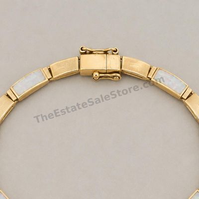 Sale Photo Thumbnail #79: Yellow-gold link bracelet featuring alternating panels of white opal-style inlay with subtle multicolor flashes. Approximate wearable length 7 inches with box clasp and safety catch. Marked 14K; estimated gross weight 12.6 grams. A few inlay panels show f