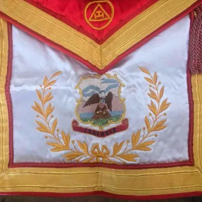 Sale Photo Thumbnail #50: A striking Masonic Royal Arch Past High Priest apron, rich in symbolism and finely detailed with gold bullion embroidery on satin.

Royal Arch Symbolism: The apron includes the characteristic red border and the emblem of the Royal Arch
Embroidered Detail: